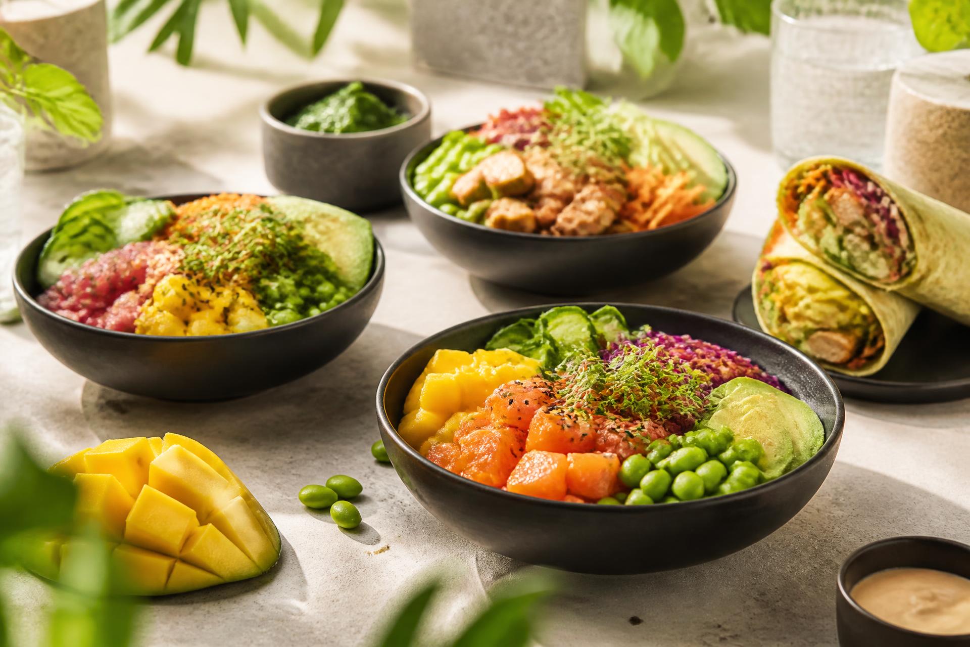 Colourful poke bowls, salad and wraps served in black bowls